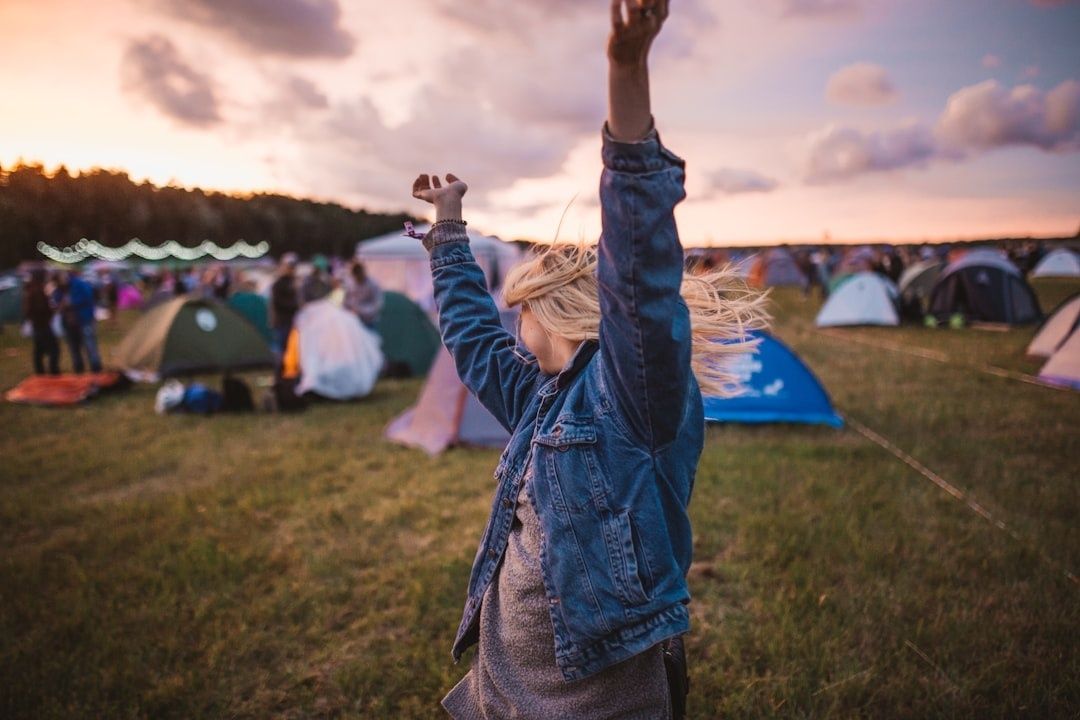 Festivalbesucherin hebt bei Sonnenuntergang auf einem Zeltplatz die Arme