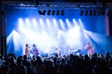 Open-Air-Konzert mit Band, blauem Licht und dichtem Publikum
